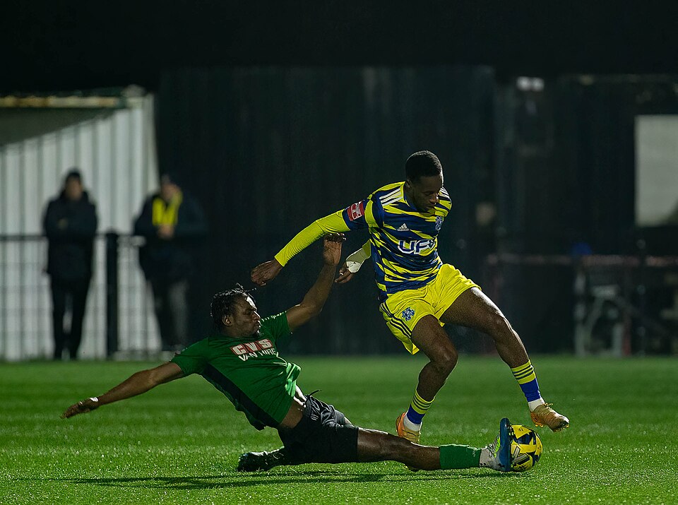 Sliding tackle on a forward carrying the ball at night